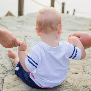 Baby holding hands on beach